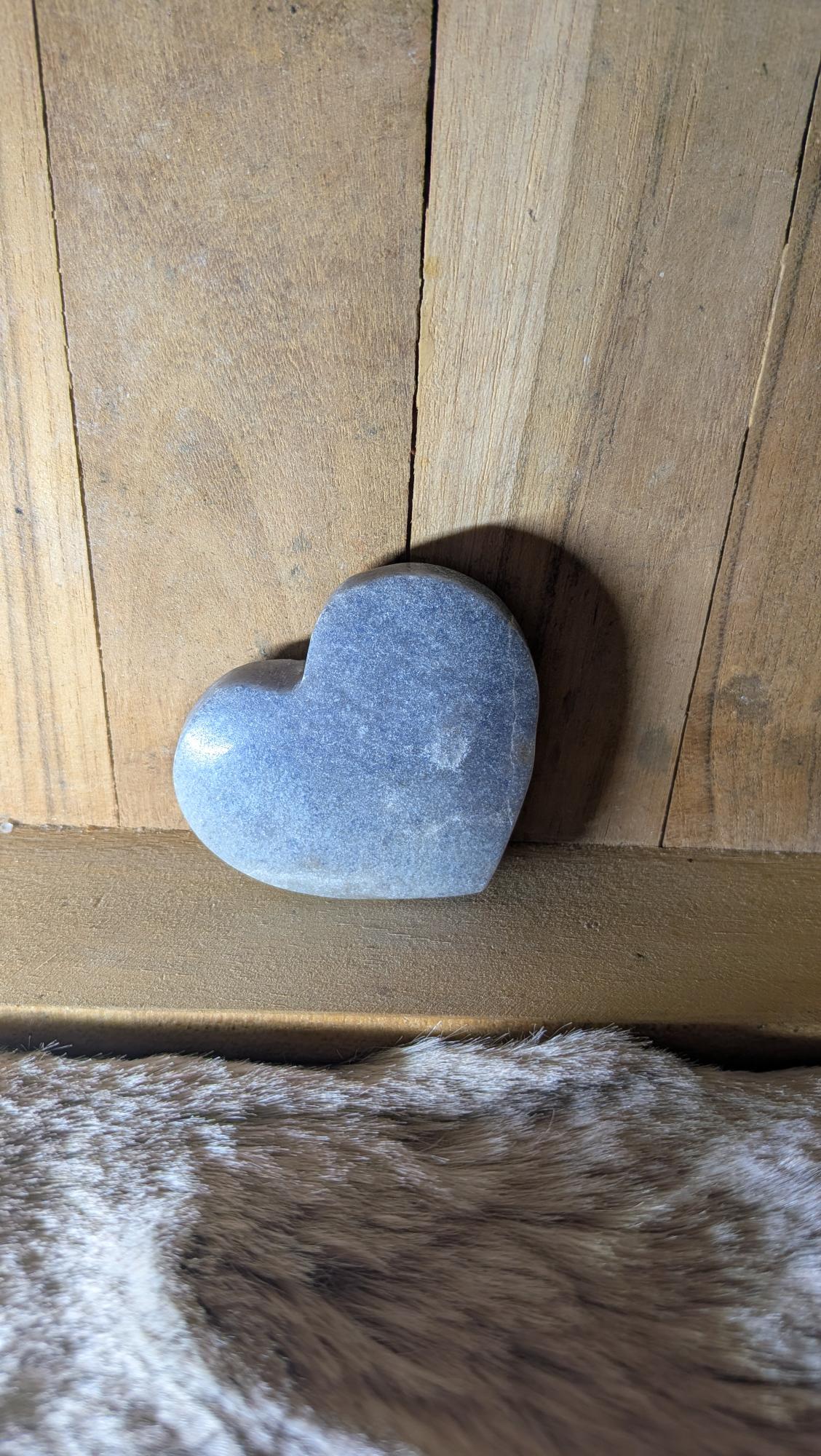 Middelmaat edelsteen hart van blauwe aventurijn met subtiele spikkeling op een houten achtergrond