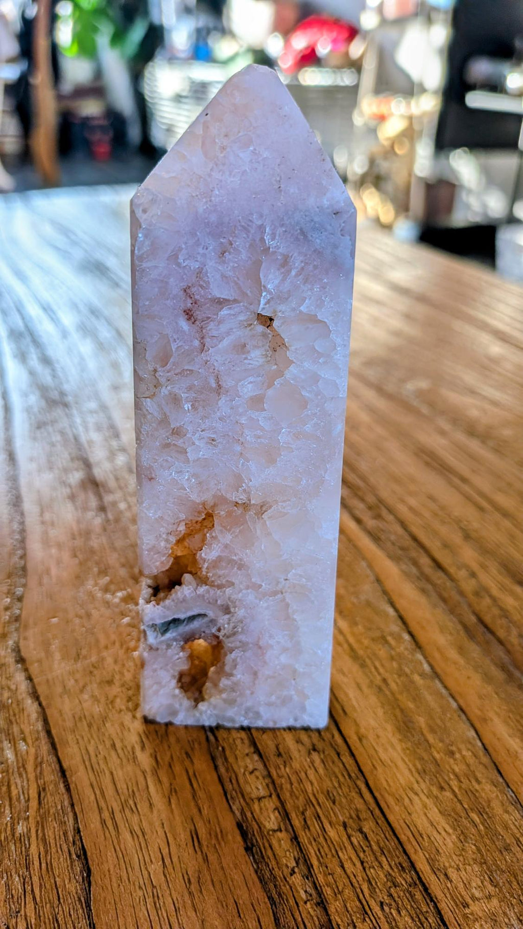 "Gepolijste kristal toren van Bloemagaat met zichtbare witte kwarts-kristallen, staand op een houten tafel met warme lichtinval."