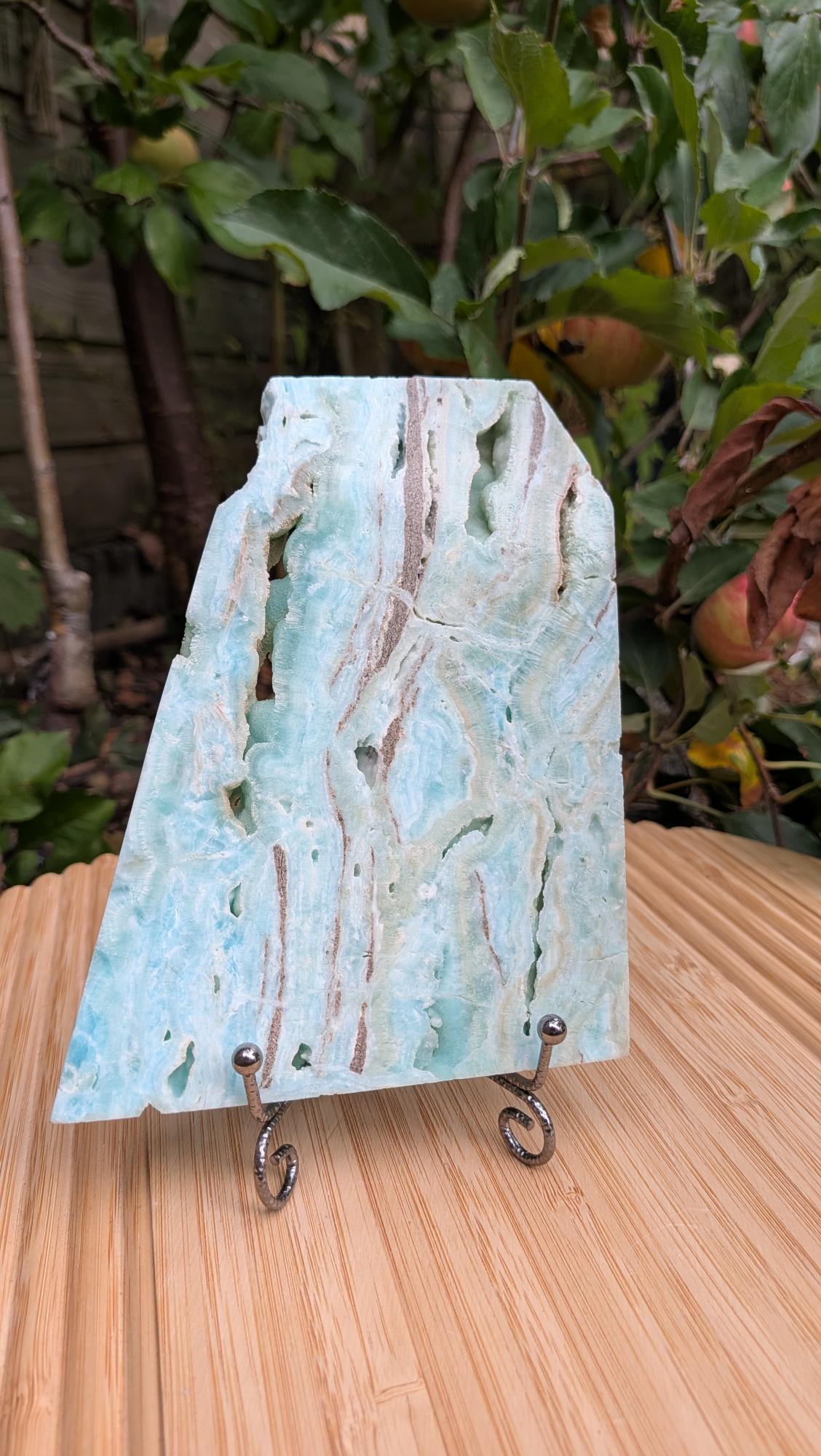 Lichtblauwe en zachtgroene Caribische calciet plak van 405 gram met natuurlijke holtes op een metalen displaystandaard