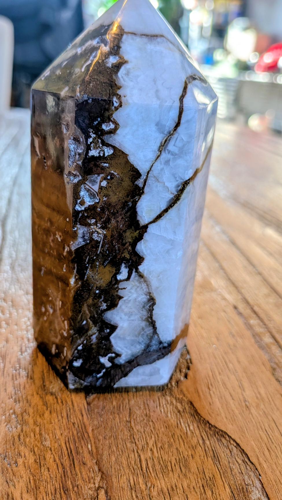 "Gepolijste Oceaan Jaspis tower uit Madagaskar met wit-bruine organische patronen, staand op een houten ondergrond."