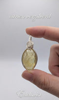 Handgemaakte wire wrapped hanger van Edeltwist met een heldere, goudgele citrien edelsteen in een verzilvende wikkeling tegen een neutrale studio achtergrond.