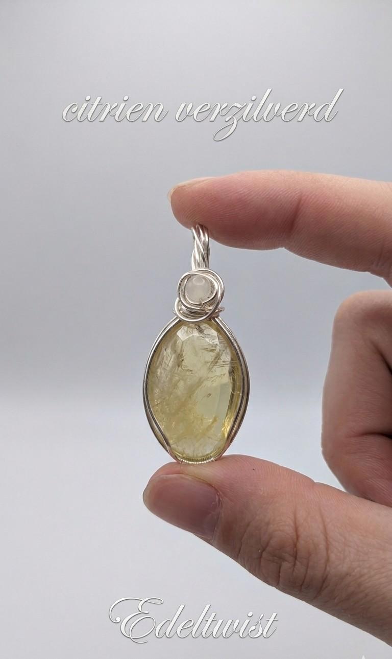 Handgemaakte wire wrapped hanger van Edeltwist met een heldere, goudgele citrien edelsteen in een verzilvende wikkeling tegen een neutrale studio achtergrond.
