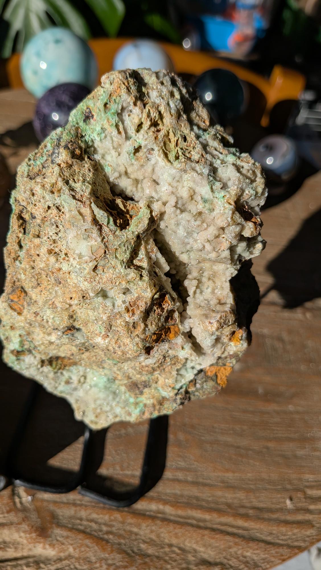 Detailopname van zachtgroene, fonkelende kristalbolletjes in de holtes van een XL Chrysocolla op standaard.