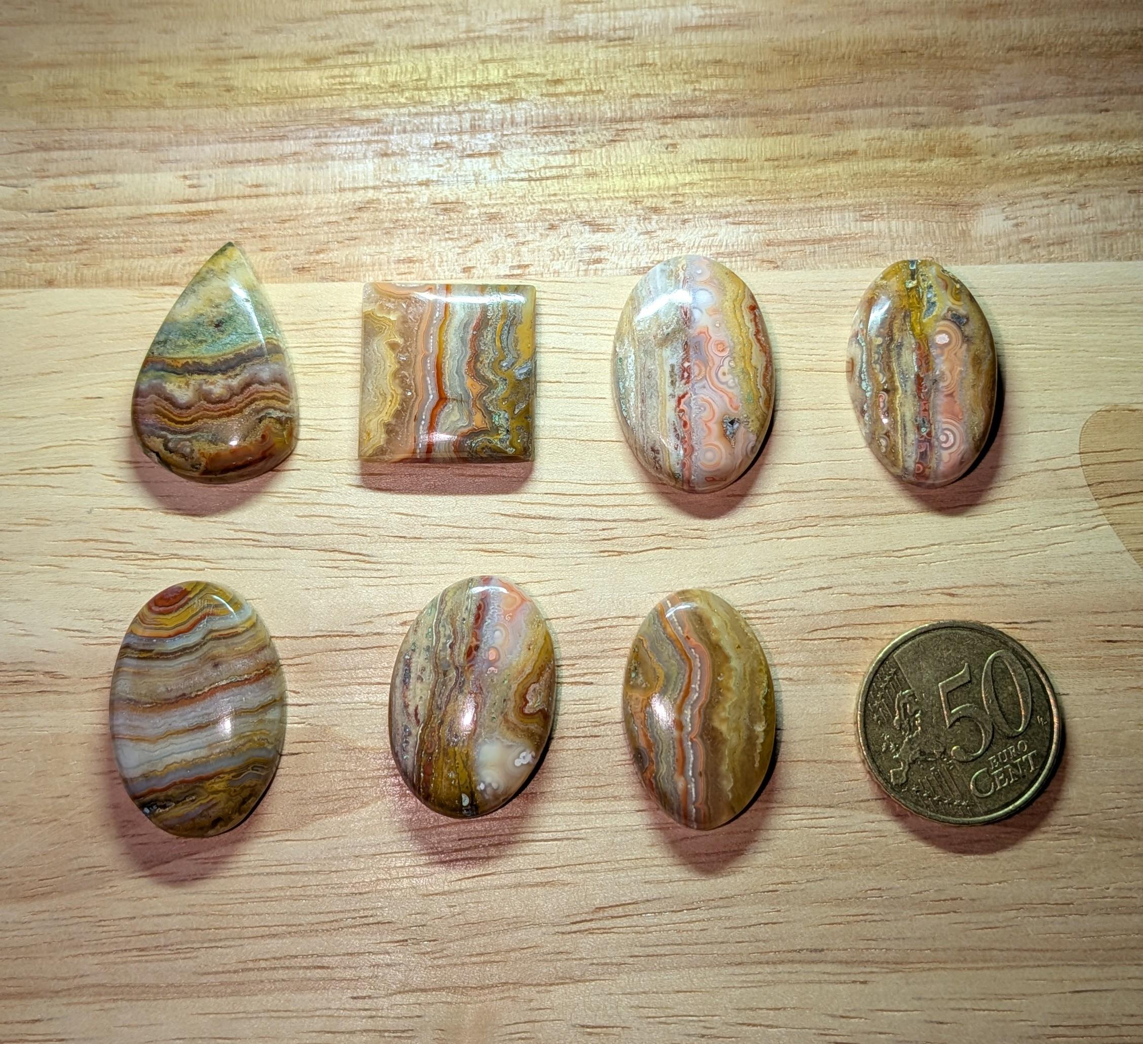 "Selectie Crazy Lace Agaat cabochons in vierkant, druppel en ovaalvorm met unieke lijnpatronen voor wire wrapping, naast een 50 cent munt."
