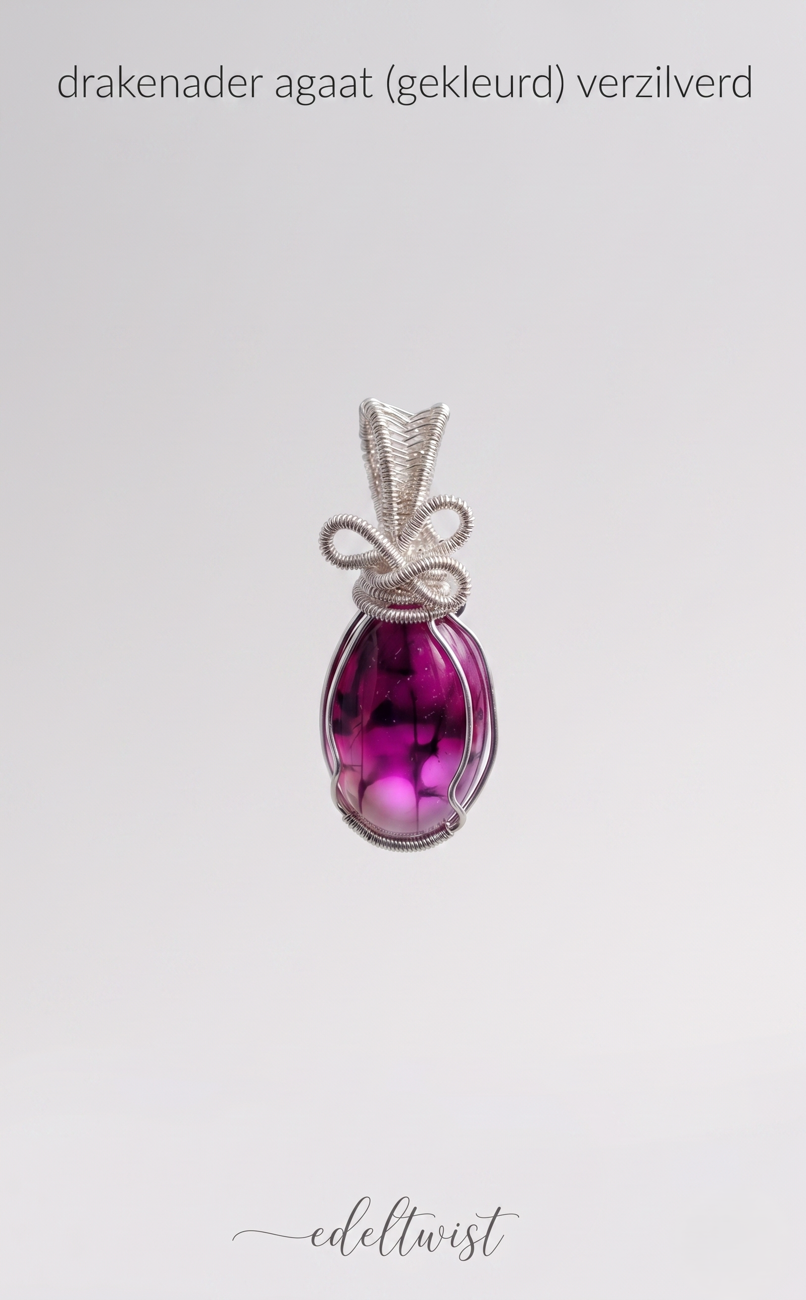 Een close-up detailopname van de unieke, handgemaakte zilveren wire-wrapped hanger met de opvallende magenta gekleurde drakenader agaatsteen. De hanger rust op een grijze vilten displaypad. De focus ligt op het ingewikkelde zilveren draadwerk, inclusief de minuscule spiralen en de complexe, handgemaakte knoopstructuur die de steen veilig vasthoudt en de bail vormt. De unieke interne patronen van de drakenader agaat, met zijn diepe magenta kleur en zwarte aders, zijn scherp en duidelijk zichtbaar. De hanger 