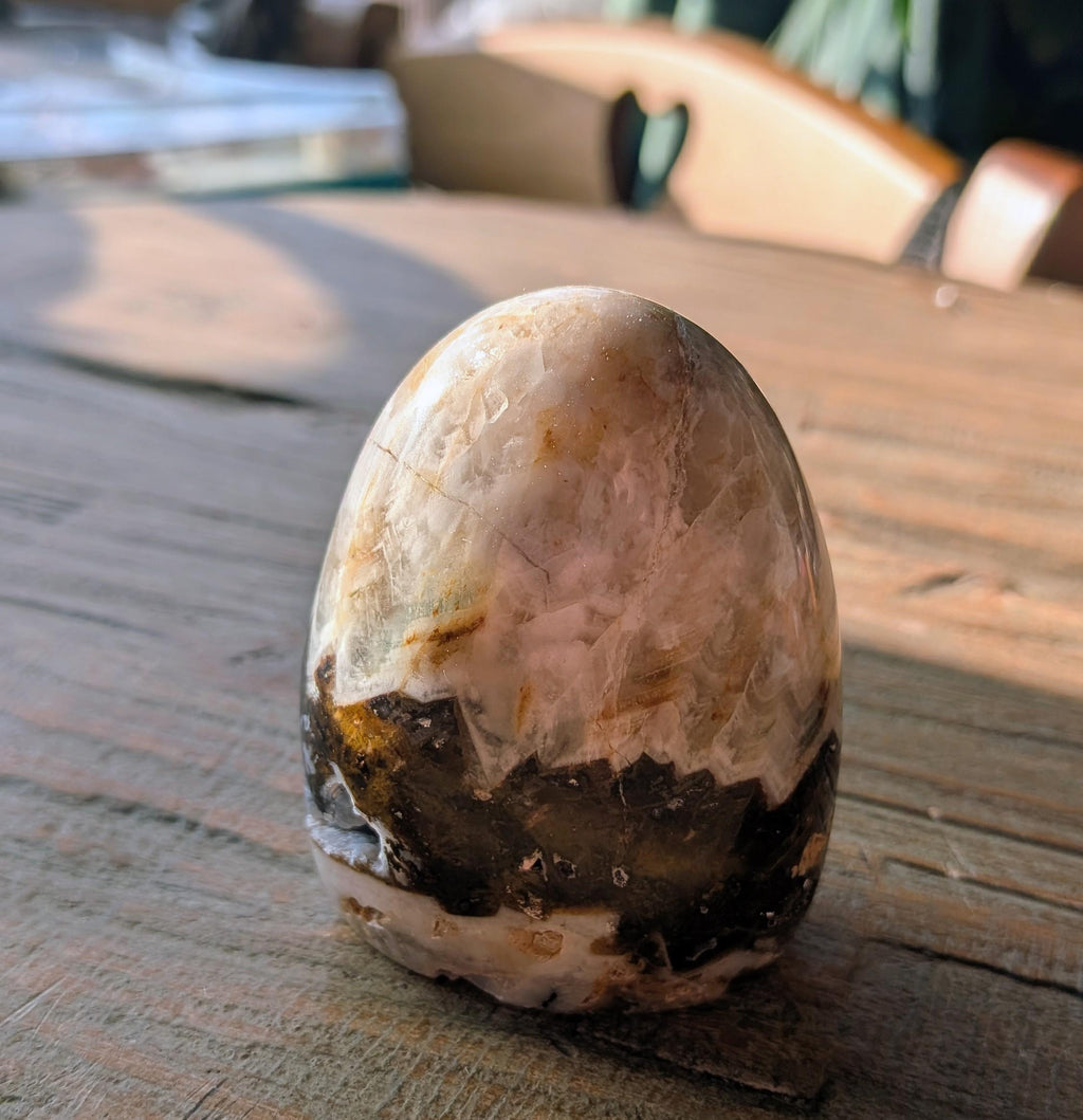 Handgepolijste Olijf Agaat freeform van 218 gram met een opvallende natuurlijke kristalholte vol fonkelende druzy, staand op een houten ondergrond.