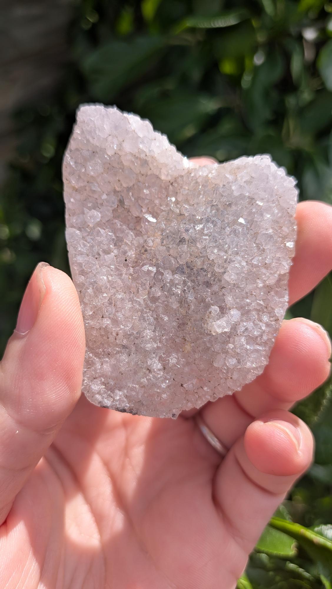 Een hand houdt een sprankelende suiker druzy chalcedoon van 39 gram vast, met een fijne, suikerachtige kristaltextuur