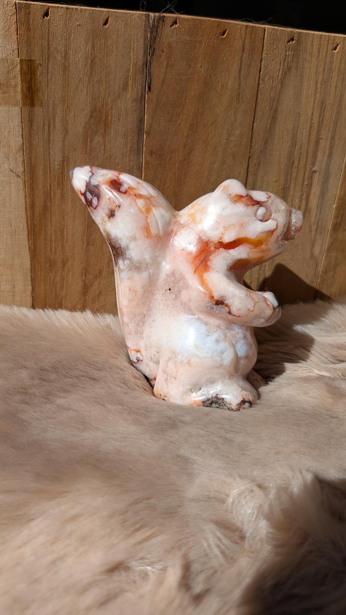 Vooraanzicht van een roze bloemagaat eekhoorn van 267 gram op een houten ondergrond.