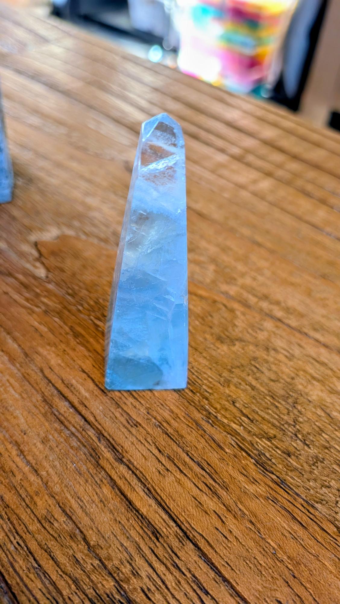 Verticale Fluoriet kristal toren van 7 cm hoog met paarse en groene kleurbanden op een houten ondergrond.