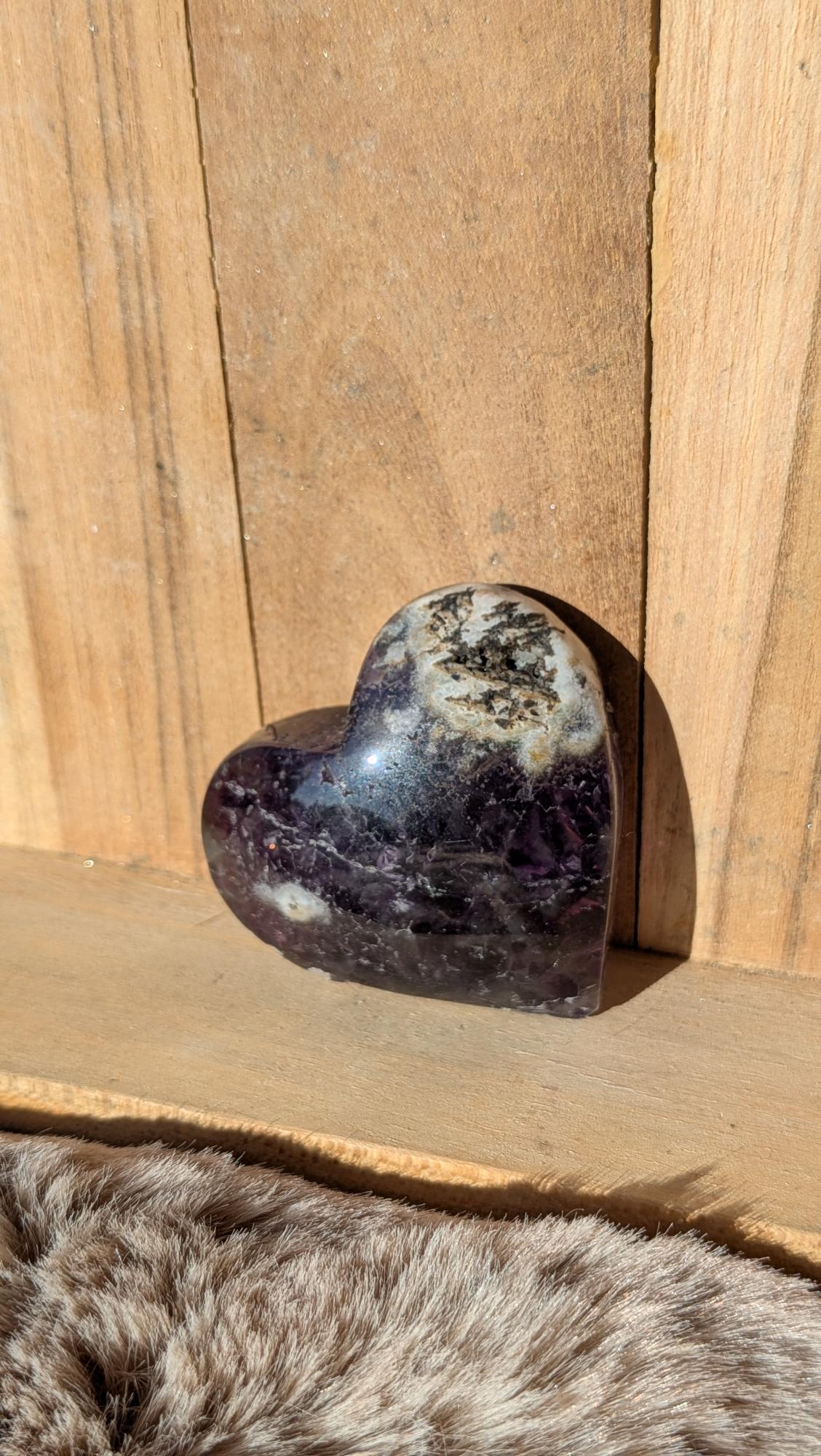 Middelmaat edelsteen hart van paarse fluoriet met natuurlijke kristalstructuren op een houten achtergrond