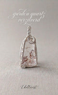 Handgemaakte Garden Quartz hanger met verzilverd wire wrap draadwerk van Edeltwist. Exclusief edelsteen sieraad met unieke landschappelijke insluitsels op een zachtgroene achtergrond.