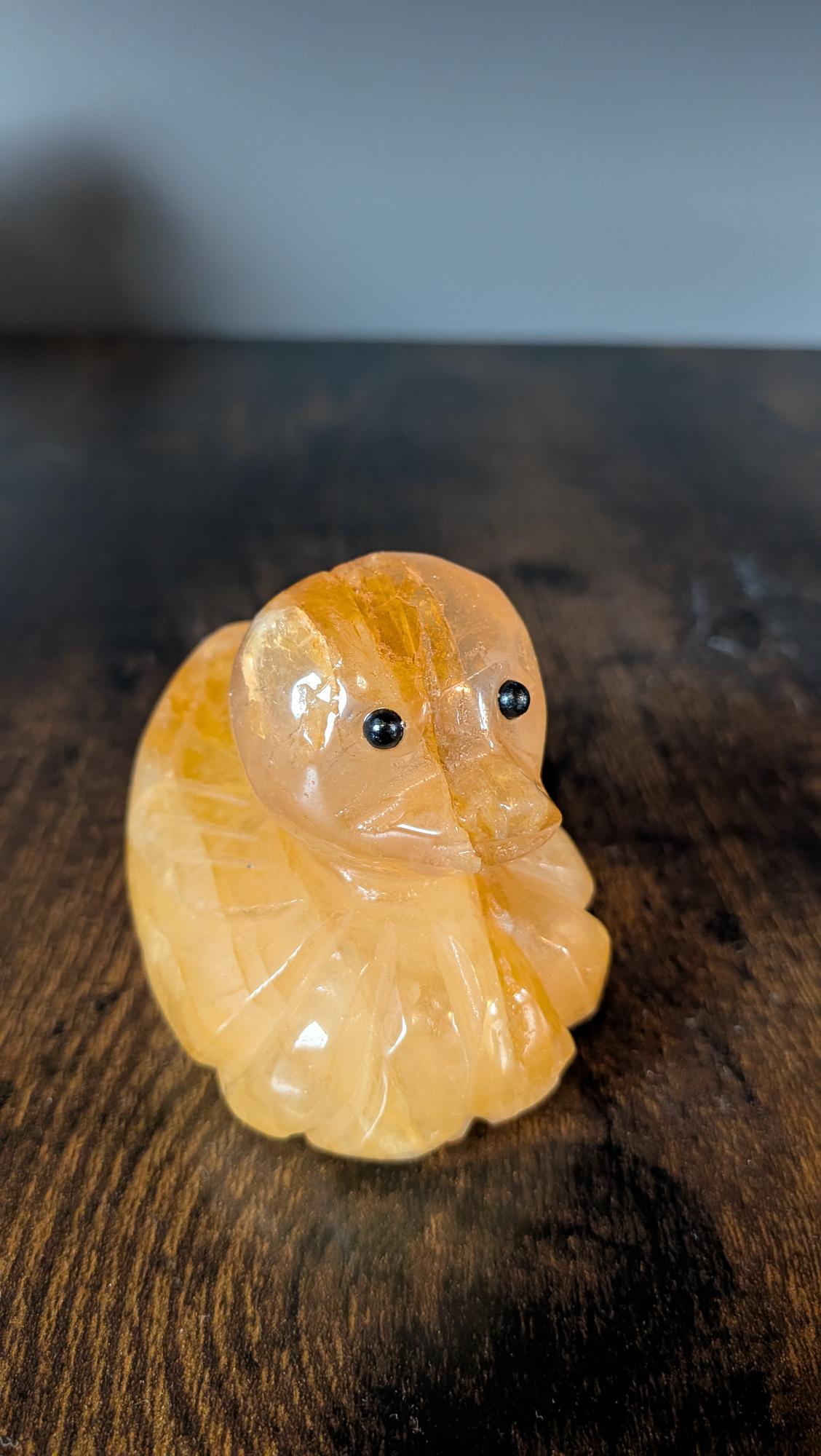 Vooraanzicht van handgesneden Golden Healer kwarts eend met zwarte oogjes Edeltwist