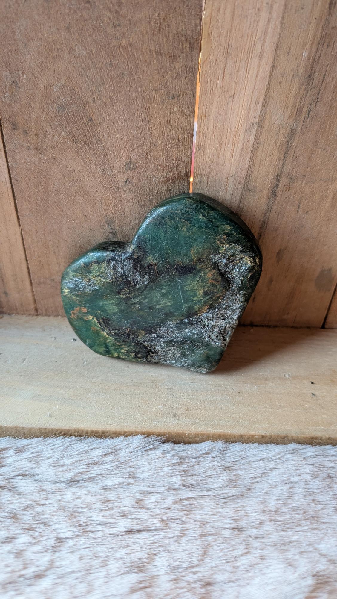 Middelmaat edelsteen hart van groene jade met natuurlijke structuur op een houten achtergrond