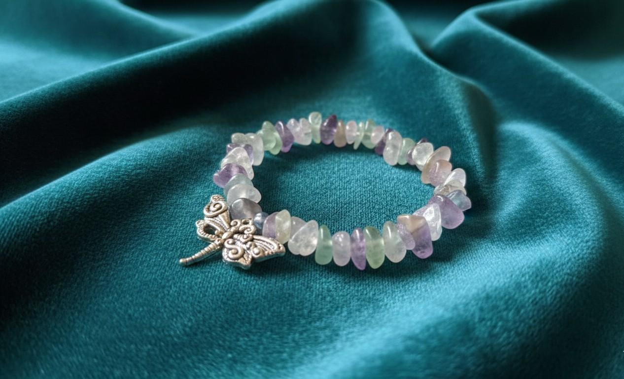 Handgemaakte armband van Fluoriet splitstenen met een zilverkleurige libel bedel op een groene fluwelen achtergrond.