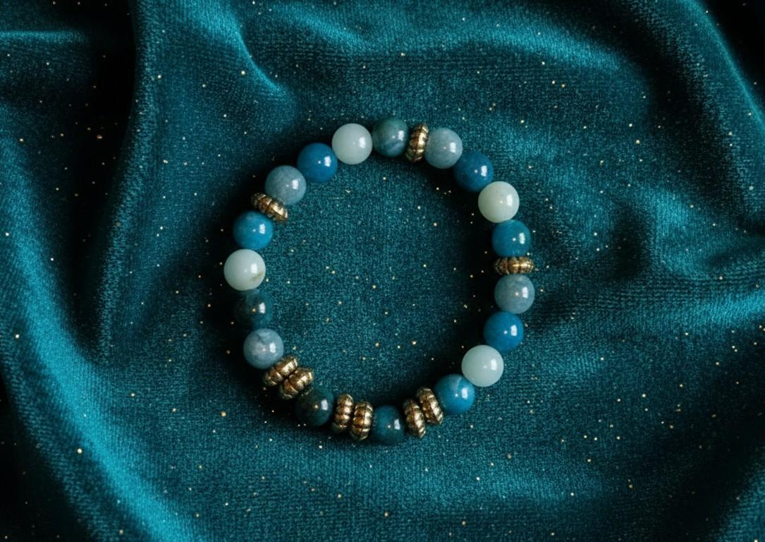 Handgemaakte armband van ronde Amazoniet edelsteenkralen met goudkleurige bewerkte tussenstukjes op een petrolblauwe fluwelen ondergrond