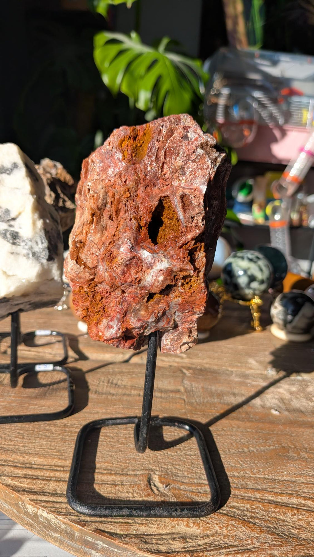 Voorzijde van een XL rode jaspis op standaard, met diepe roodbruine kleuren en okergele minerale holtes.