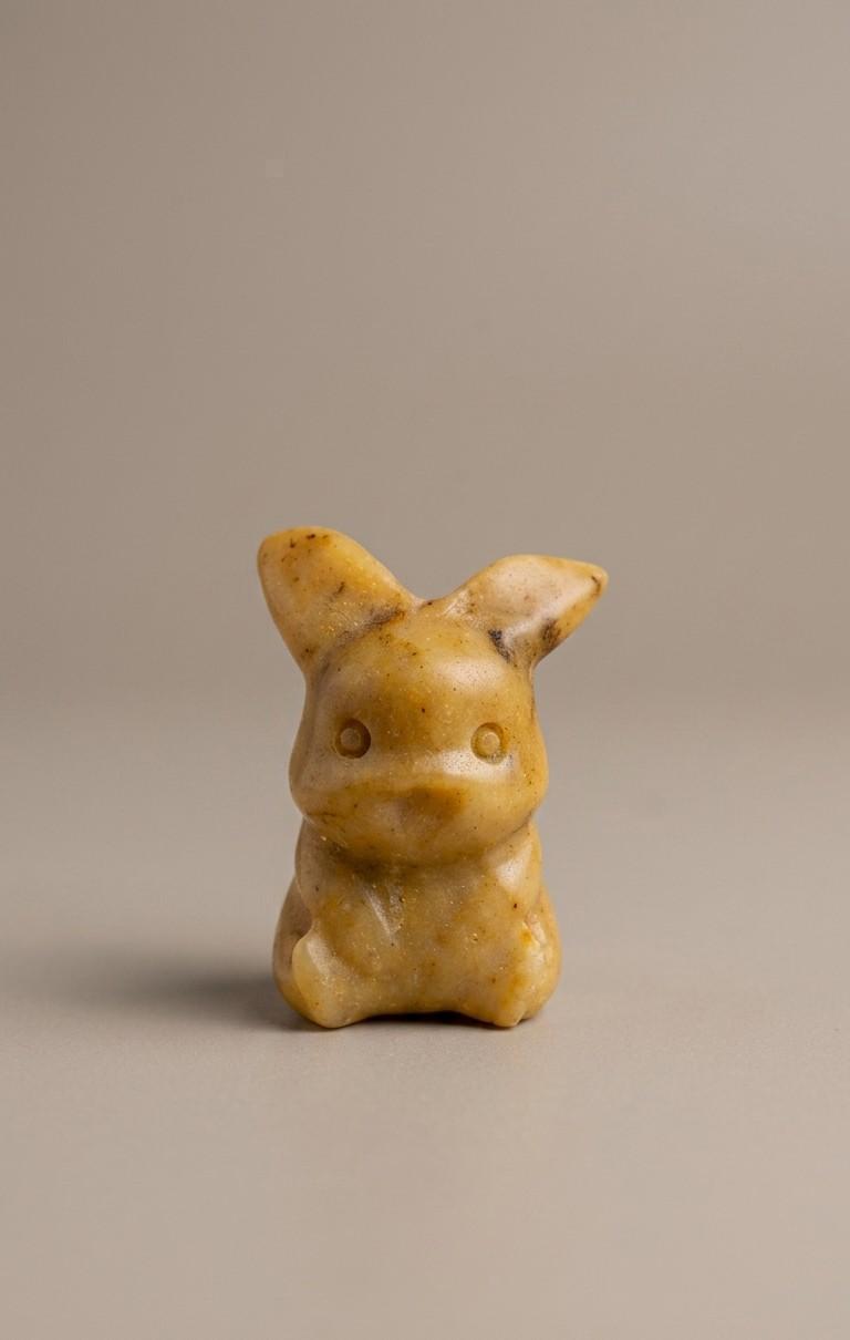 Handgeslepen edelsteen figuurtje van een zittende gele Pokémon (Pikachu), vervaardigd uit ondoorzichtige okergele jaspis met subtiele natuurlijke patronen.