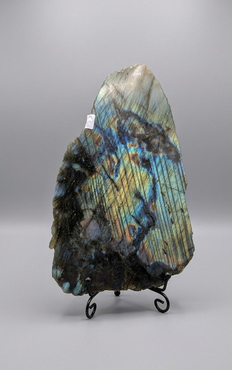 Gepolijste labradoriet slab met intense blauwe en koperen kleurflitsen op een elegante zilverkleurige metalen standaard van Edeltwist.