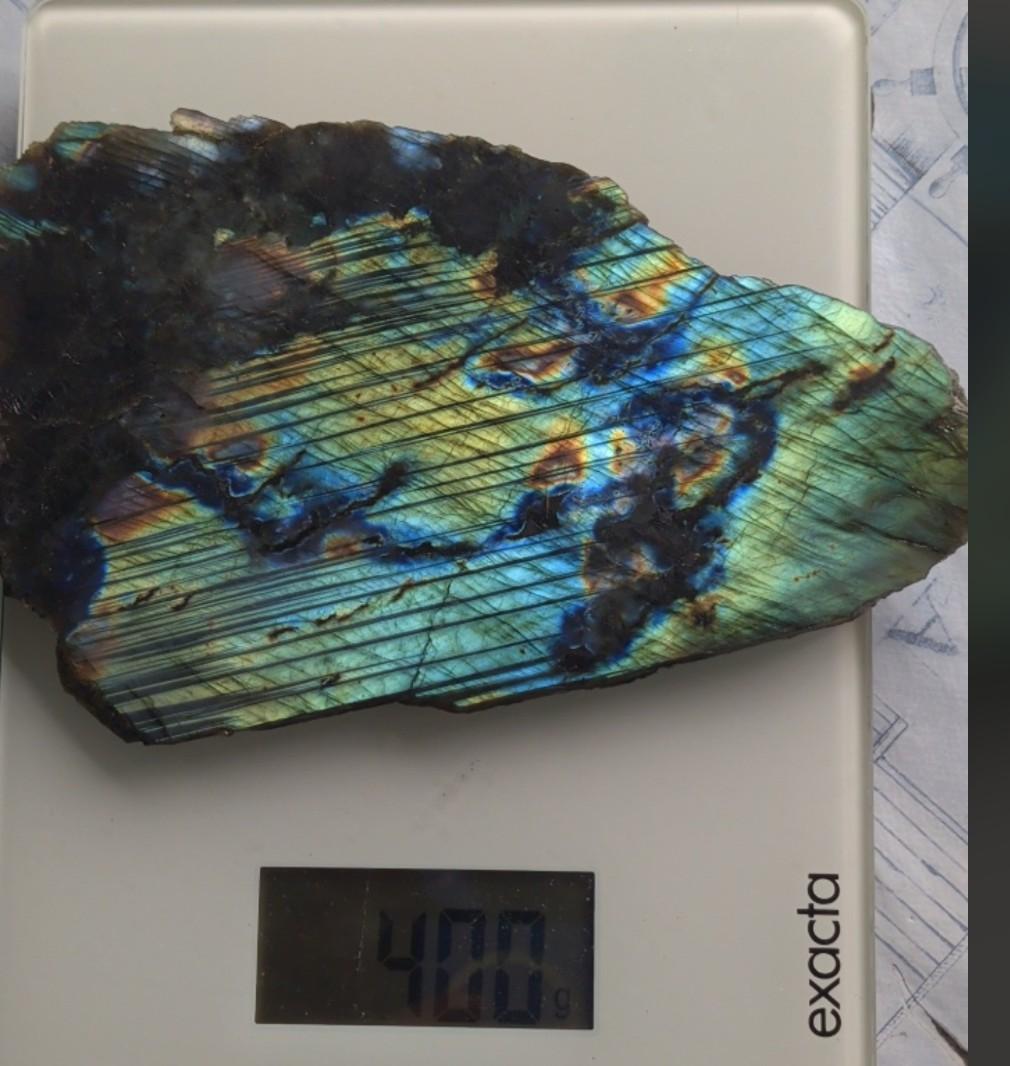 Close-up van de labradorescentie van een labradoriet plak met felle elektrisch blauwe en neongroene tinten.