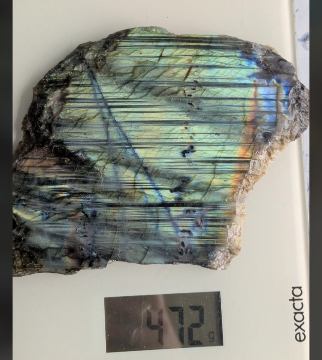 Natuurlijke ruwe structuur van labradoriet op een weegschaal met een gewicht van 472 gram.