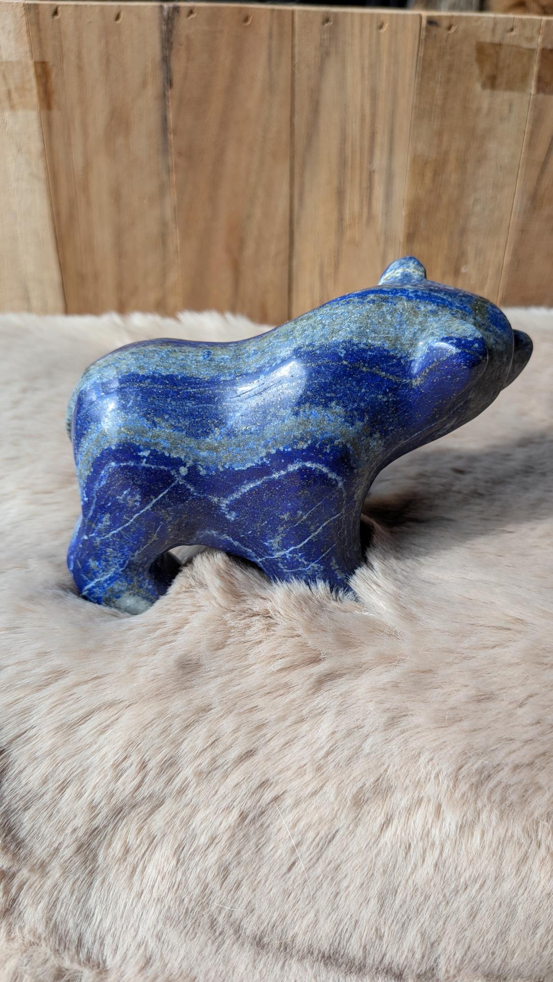 Vooraanzicht van een zware lapis lazuli beer van 554 gram op een houten ondergrond.