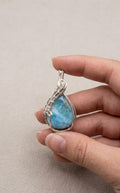 Handgemaakte druppelvormige Larimar hanger met gedetailleerd sterling zilveren wire-wrap vlechtwerk van Edeltwist, zoals getoond in 35977.png.