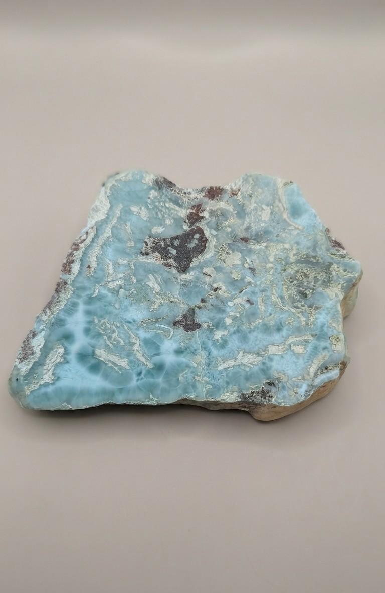 Grote, oceaanblauwe Larimar plak met wolkachtige patronen op een plastic standaard, formaat 11x8 cm.