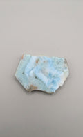 Natuurlijk larimar plakje van 40 x 28 mm met prachtige blauwe oceaanpatronen, gefotografeerd op een neutrale achtergrond.