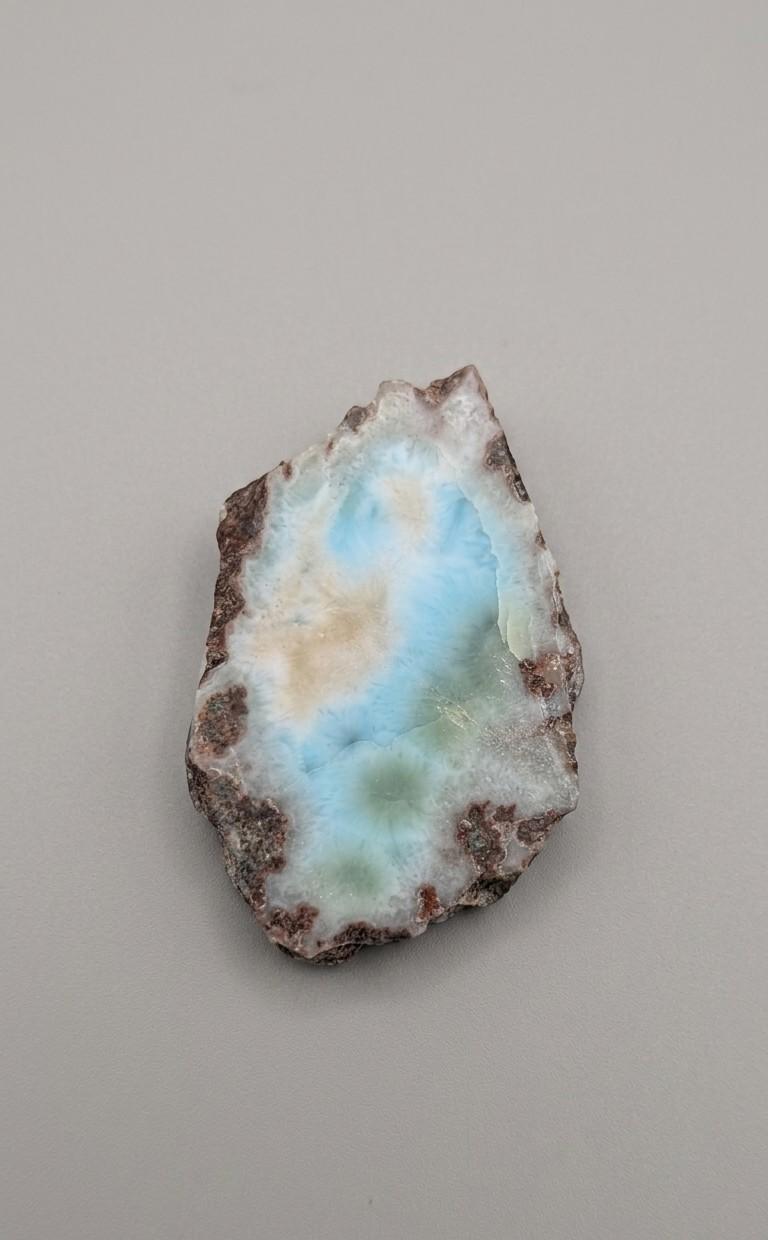 Natuurlijk larimar plakje van 43 x 31 mm met organische vorm en blauw-groene tinten, gefotografeerd op een neutrale achtergrond.