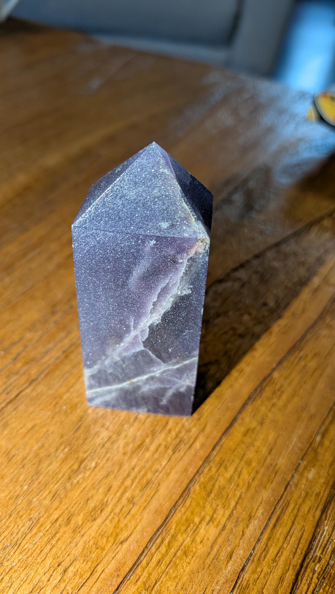 Verticale paarse Lepidoliet kristal toren van 8 cm hoog op een houten achtergrond, gewicht 99 gram.