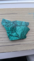 Gepolijst stuk malachiet met diepgroene patronen in de vorm van een wolvenkop, afmeting 7 bij 6.5 cm.