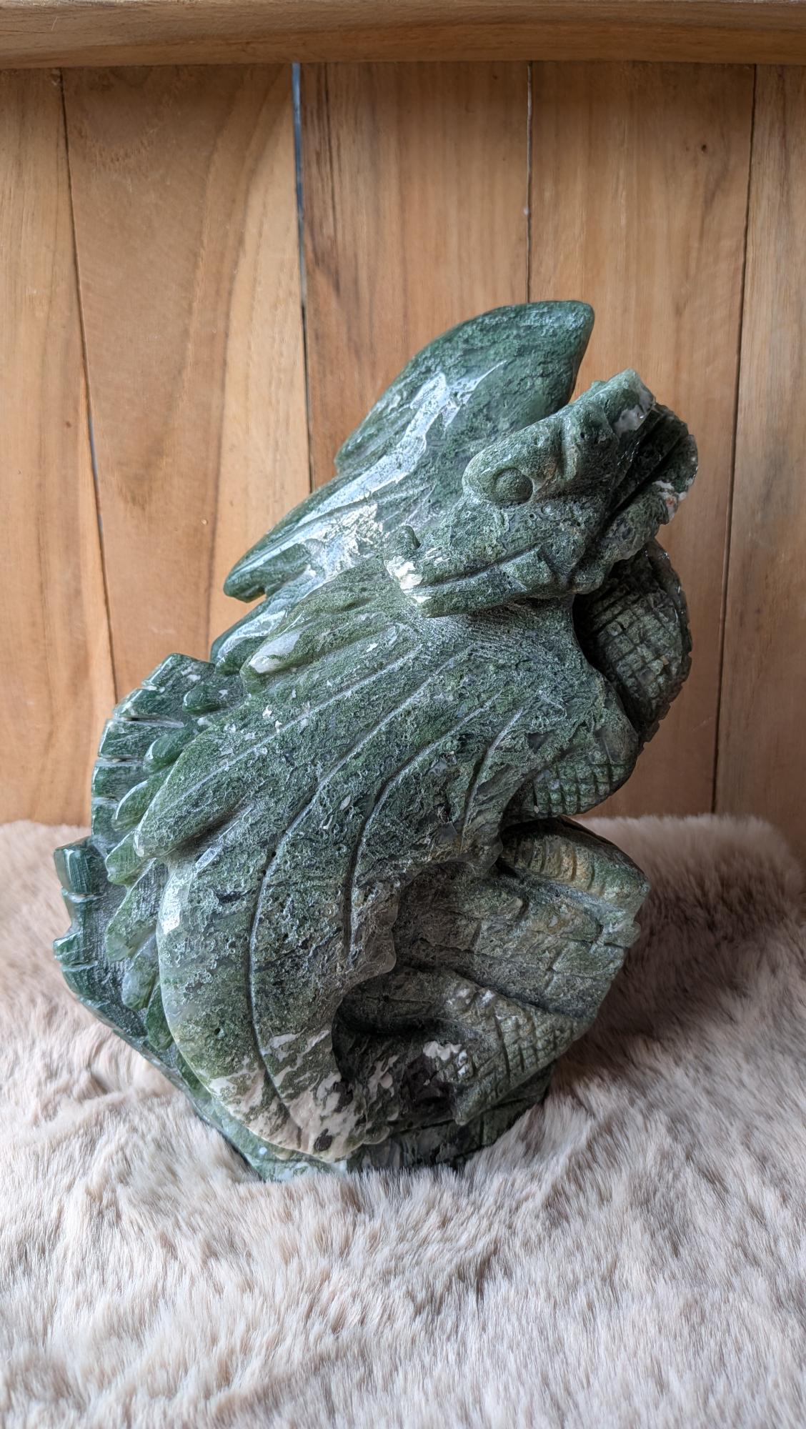 Vooraanzicht van een zware mosagaat draak van ruim 2 kilo op een houten ondergrond.