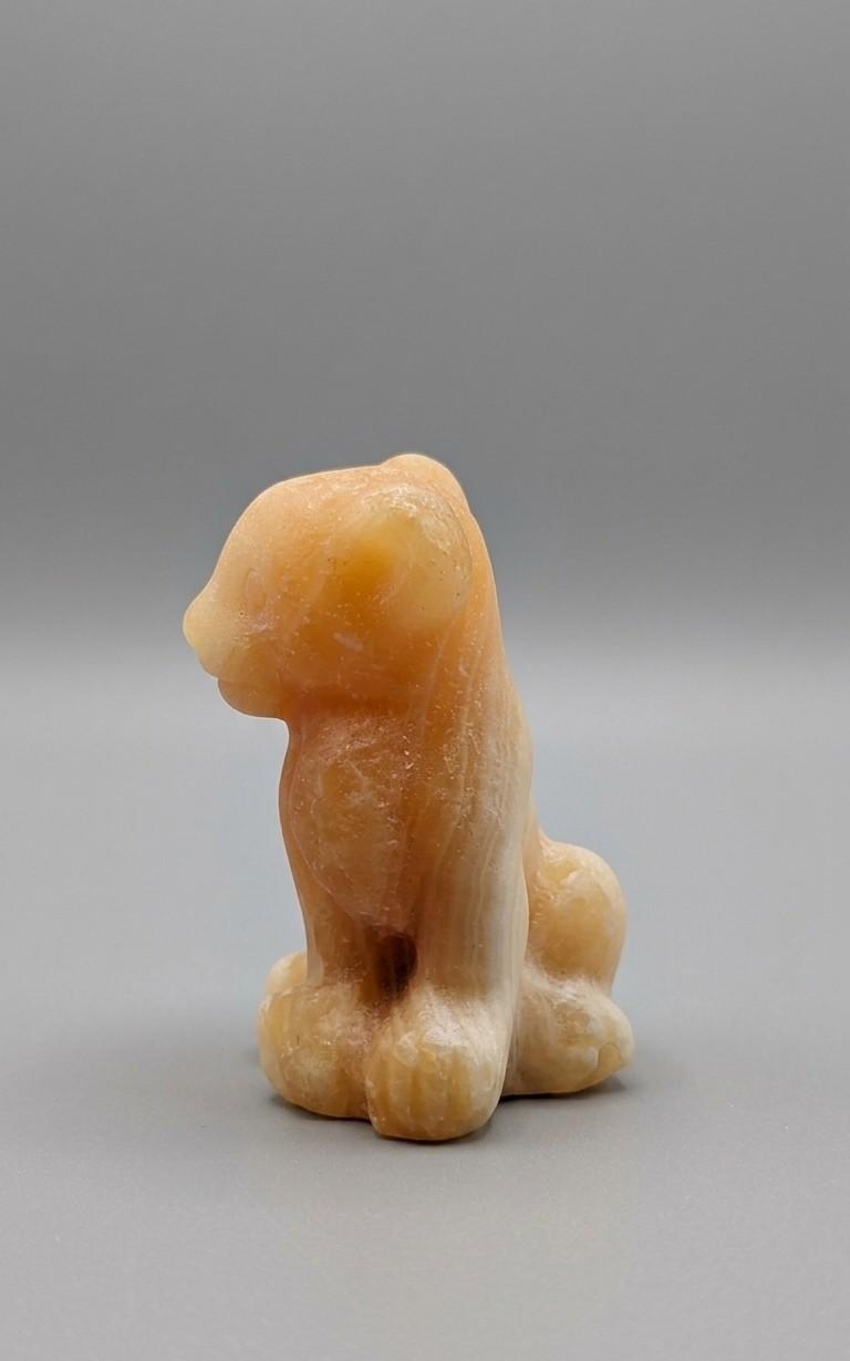 Gedetailleerd edelsteen figuur van de leeuwenwelp Nala, geslepen uit warme Gele Calciet met een zachte glans, zittende houding.