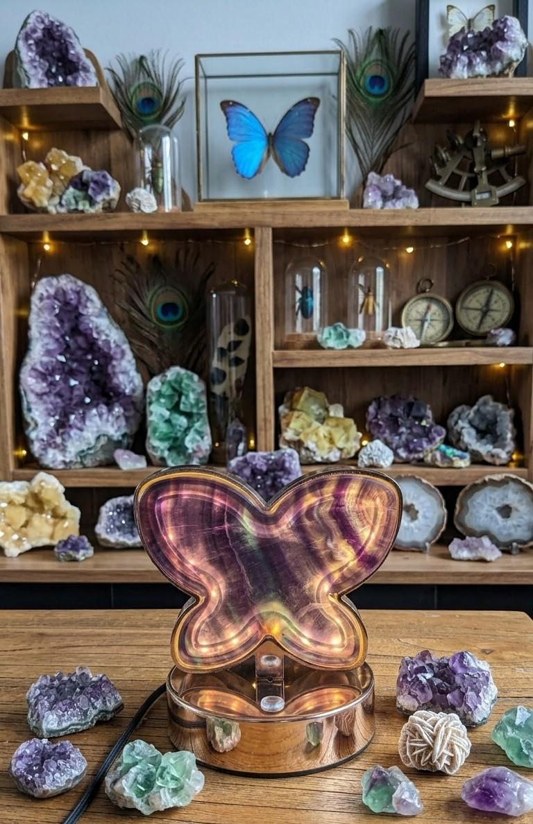 Lichtgevende vlinderlamp gemaakt van paars en groen fluoriet kristal op een houten tafel.