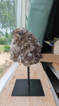 Een rookkwarts cluster van 890 gram op een zwarte standaard, met zicht op de diepe rokerige kristalstructuur