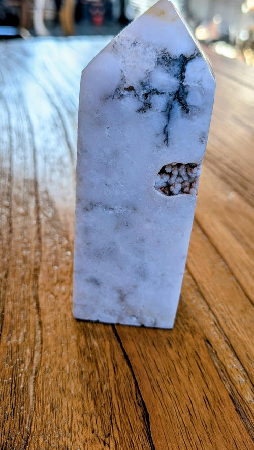 "Gepolijste Roze Amethist tower met Bloemagaat insluitingen op een houten ondergrond, uniek kristal in zachtroze en witte tinten."