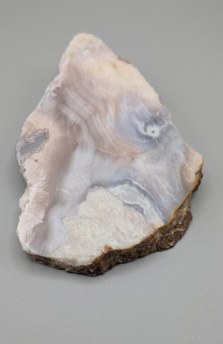 Detailopname van de semitransparante gelaagdheid en glasachtige glans van een grote roze chalcedoon plak van 183 gram.