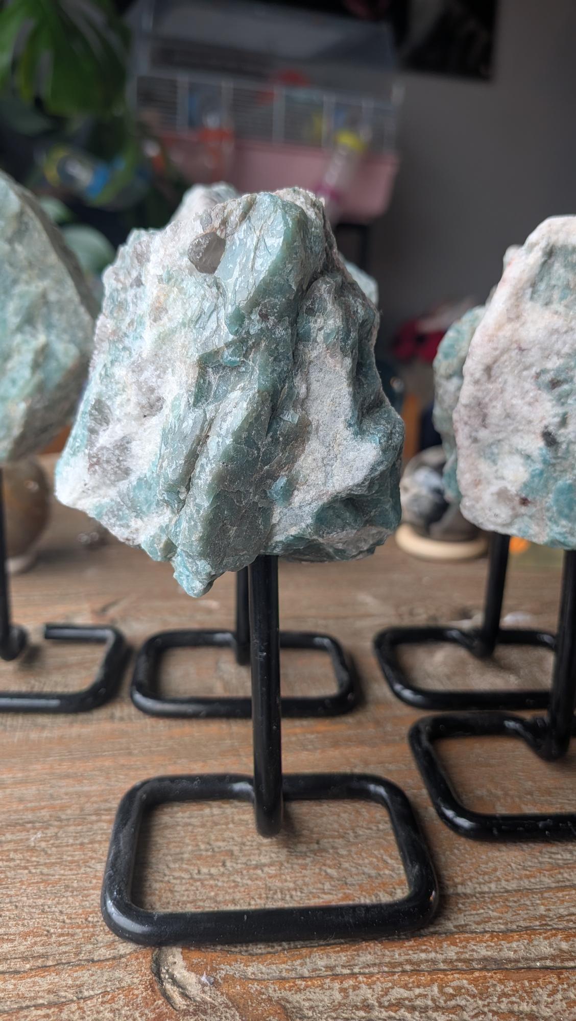 Ruwe diepgroene Amazoniet edelsteen op zwarte metalen standaard, exemplaar #210, 300 gram zwaar en 14 cm hoog.