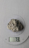 Een compact, ruw cluster van goudkleurige Pyrietkristallen en heldere kwartsdeeltjes, gewogen op een digitale weegschaal die 73 gram aangeeft.