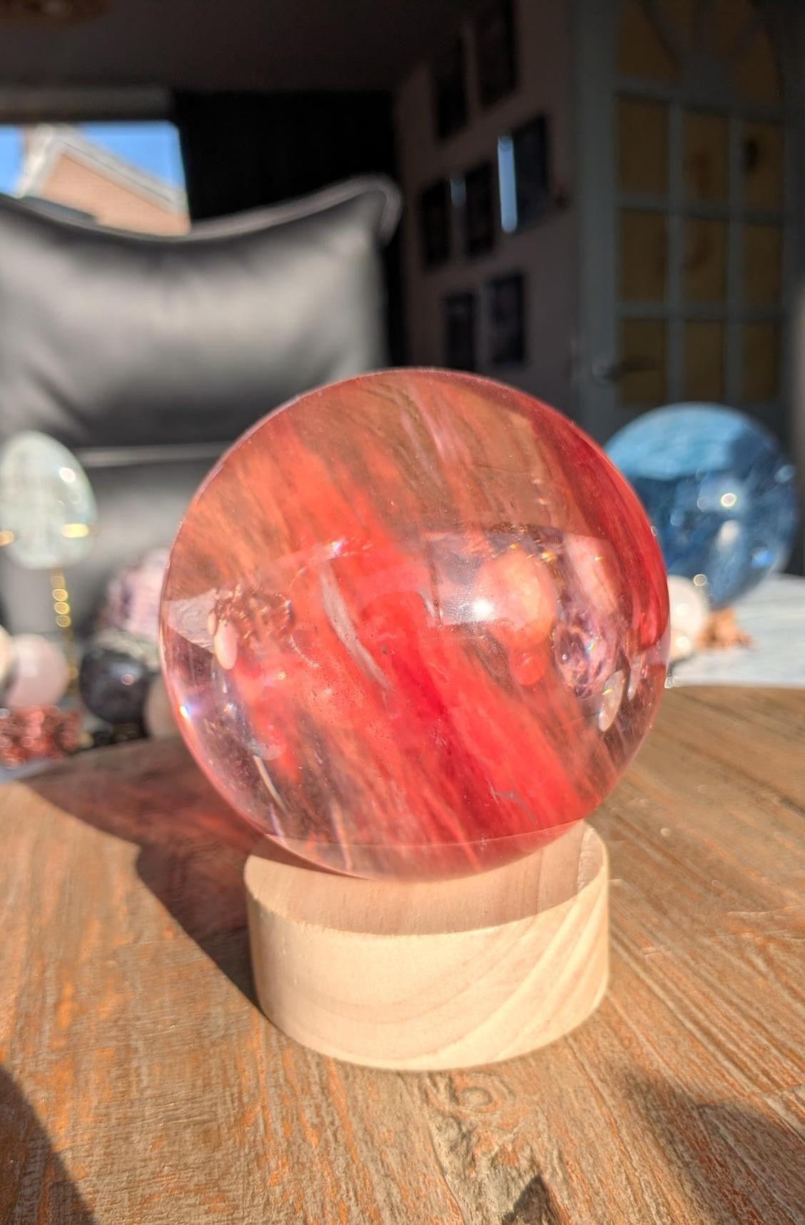 Een massieve, heldere smeltkwarts bol van 10 cm op een ronde houten LED-standaard die de bol van binnenuit verlicht met een warme gloed.