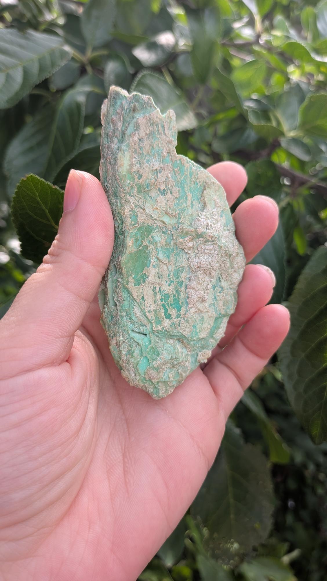 Een hand houdt een mintgroen Smithsoniet-stuk van 70 gram vast, met een unieke natuurlijke textuur