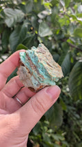 Een hand houdt een gelaagd, mintgroen Smithsoniet-stuk van 84 gram vast, met een robuuste, natuurlijke textuur