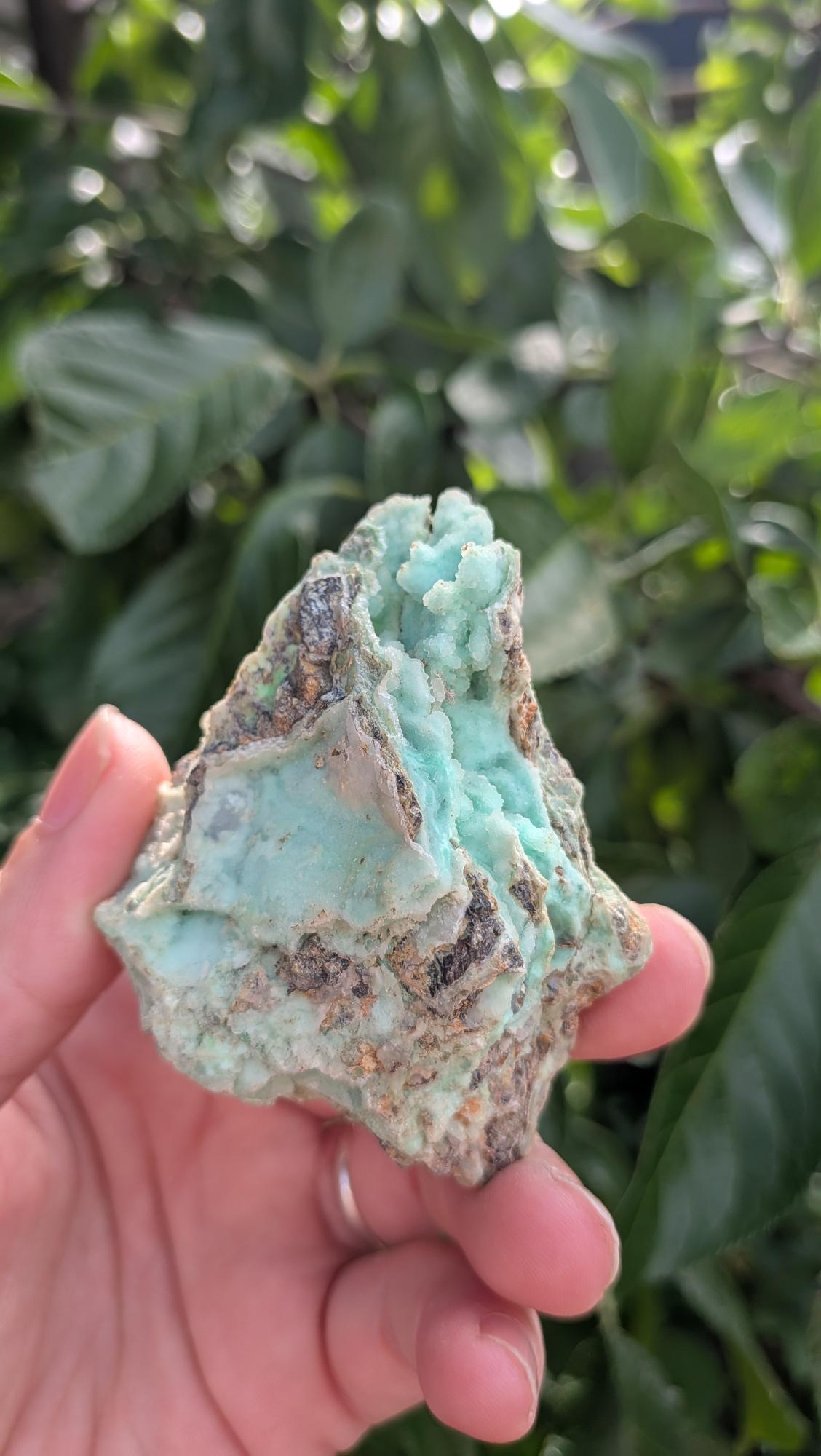 Een hand houdt een mintgroen Smithsoniet-stuk van 68 gram vast, met een robuuste, natuurlijke textuur
