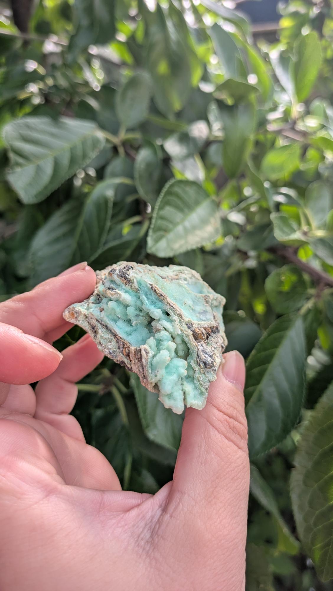 Een hand houdt een mintgroen Smithsoniet-stuk van 68 gram vast, met een robuuste, natuurlijke textuur