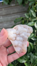 Een hand houdt een sprankelende suiker druzy chalcedoon van 47 gram vast, met een fijne, suikerachtige kristaltextuur