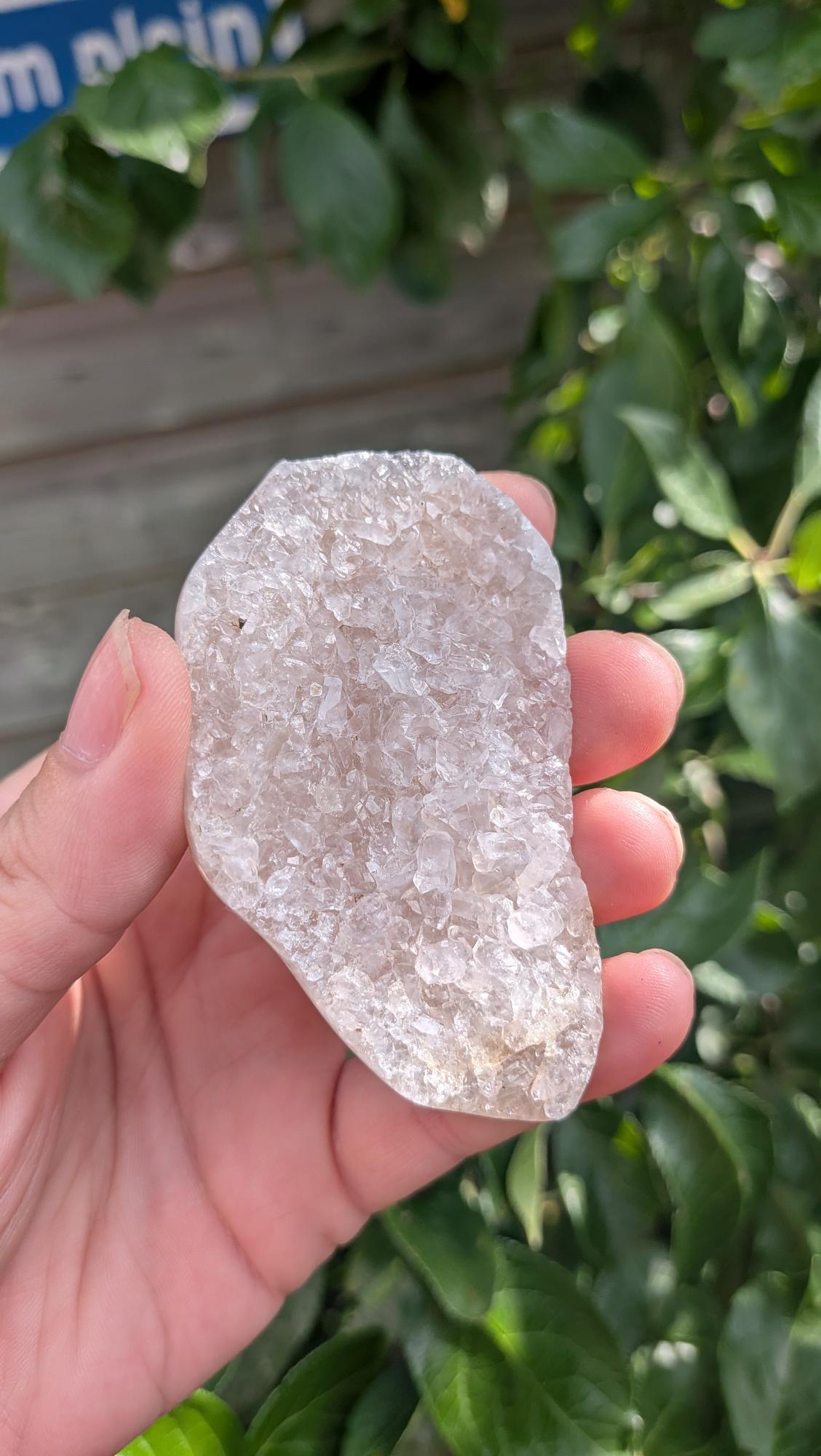 Een hand houdt een sprankelende suiker druzy chalcedoon van 48 gram vast, met een fijne, suikerachtige kristaltextuur