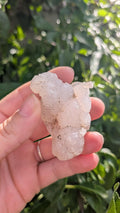 Een hand houdt een sprankelende suiker druzy chalcedoon van 50 gram vast, met een fijne, suikerachtige kristaltextuur