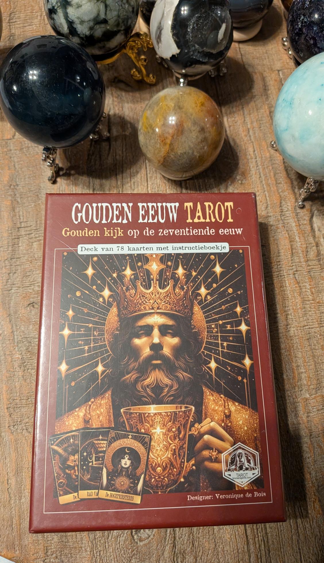 Vooraanzicht van de Gouden Eeuw Tarotbox door Veronique de Bois, roodbruine verpakking met gouden koningsfiguur en drie voorbeeldkaarten op een houten ondergrond