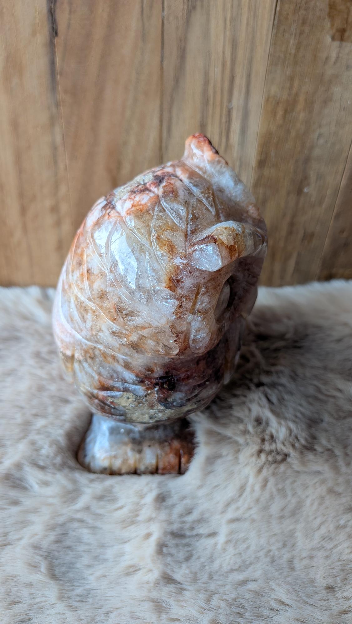 Vooraanzicht van een zware bloemagaat uil van ruim een kilo op een houten ondergrond.