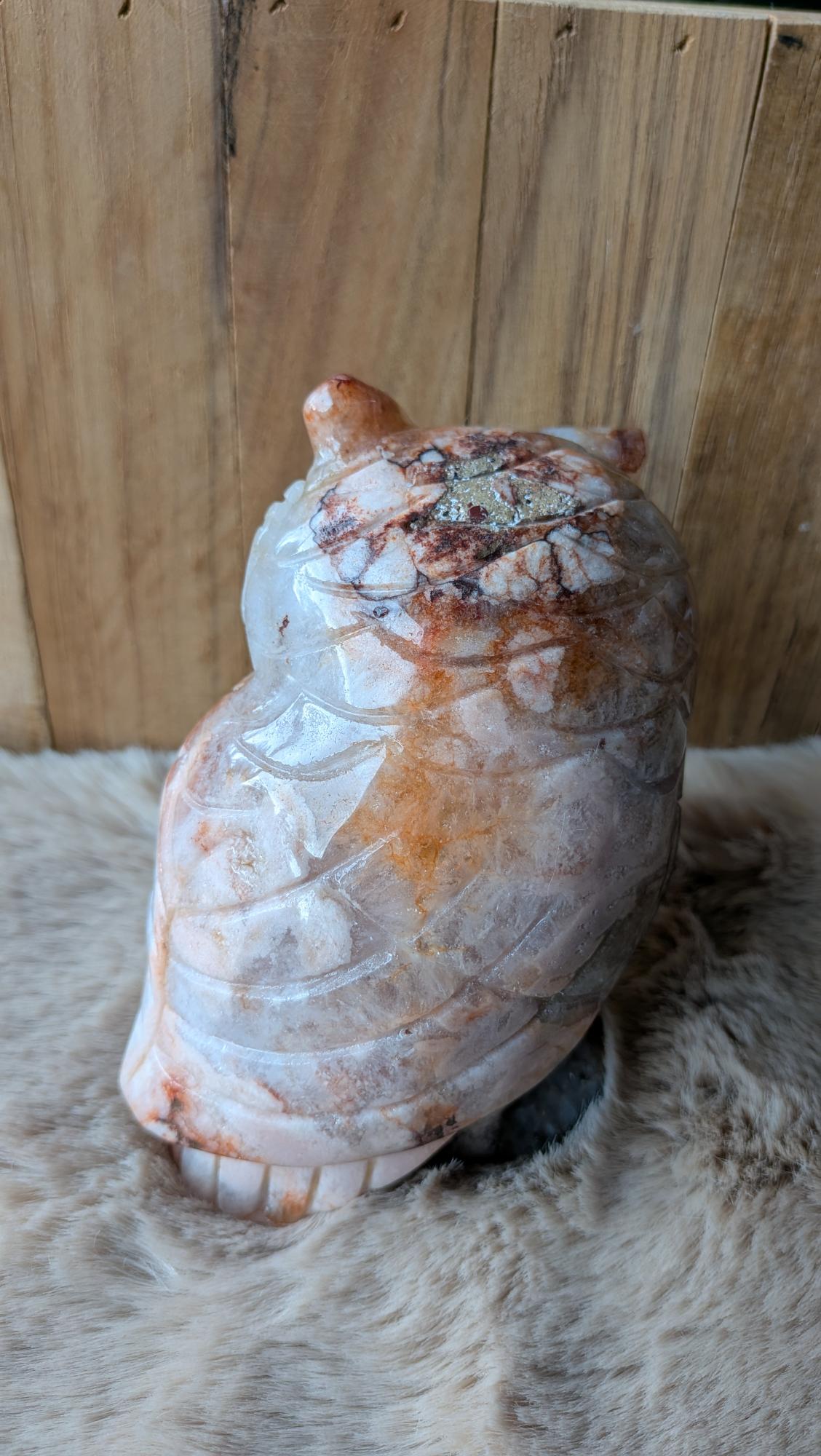 Achteraanzicht van een zware bloemagaat uil van ruim een kilo op een houten ondergrond.